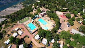 Vista aerea di un resort con due piscine, uno scivolo acquatico e un campo da tennis.