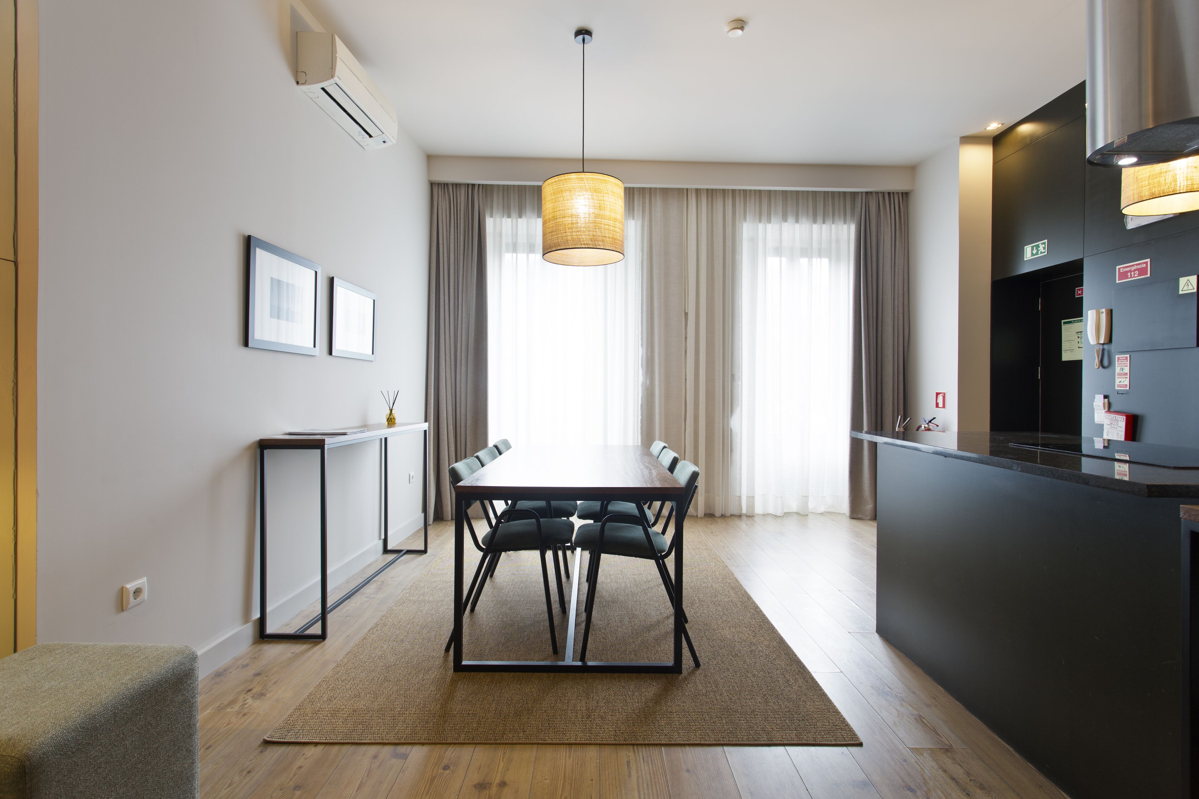A modern kitchen with a dining table, chairs, and a hanging light fixture.