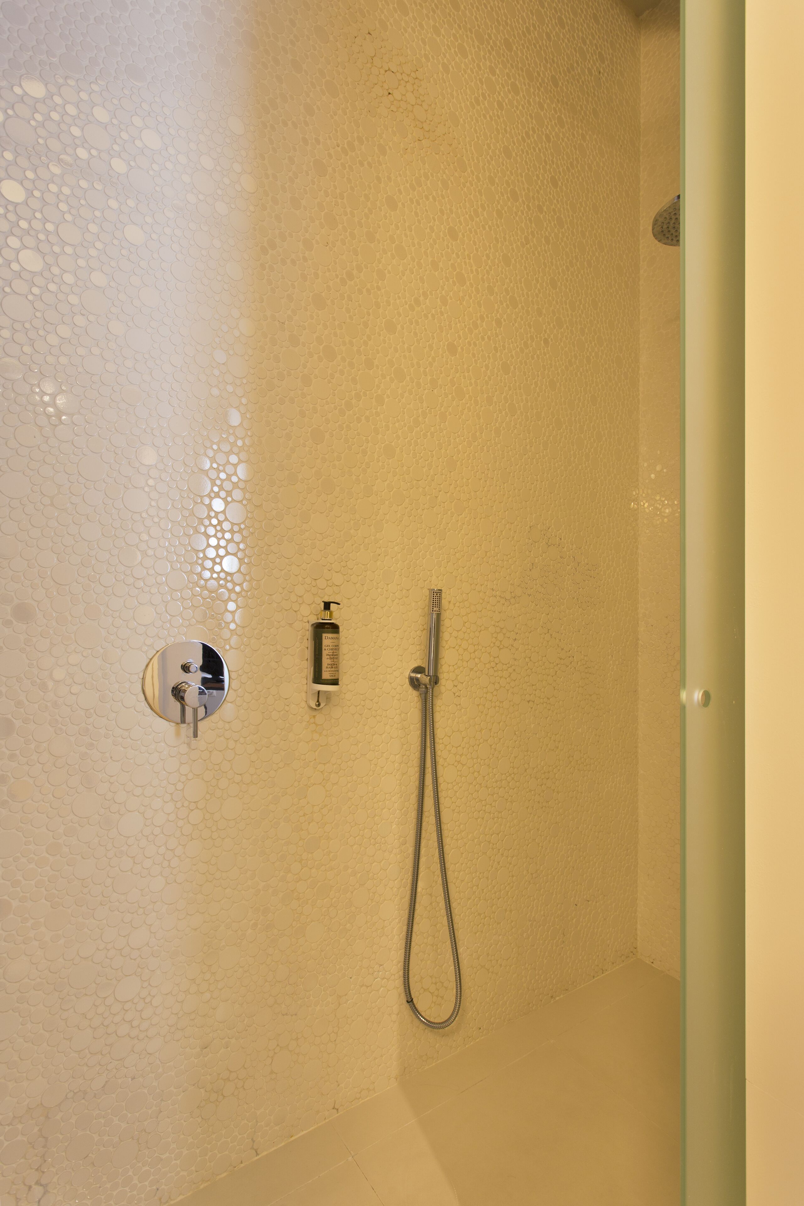 Een douche met een handdouche en een kraan op de muur.