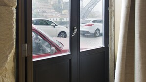 Udsigt gennem en dør, der viser parkerede biler og en bro i baggrunden.