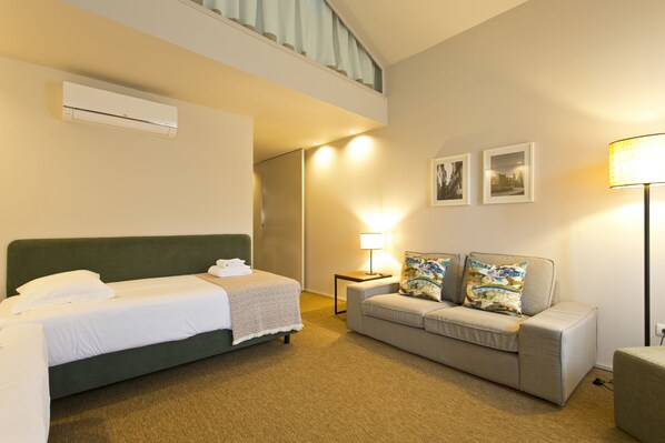 A hotel room with a bed, a sofa, a lamp, and a picture on the wall.