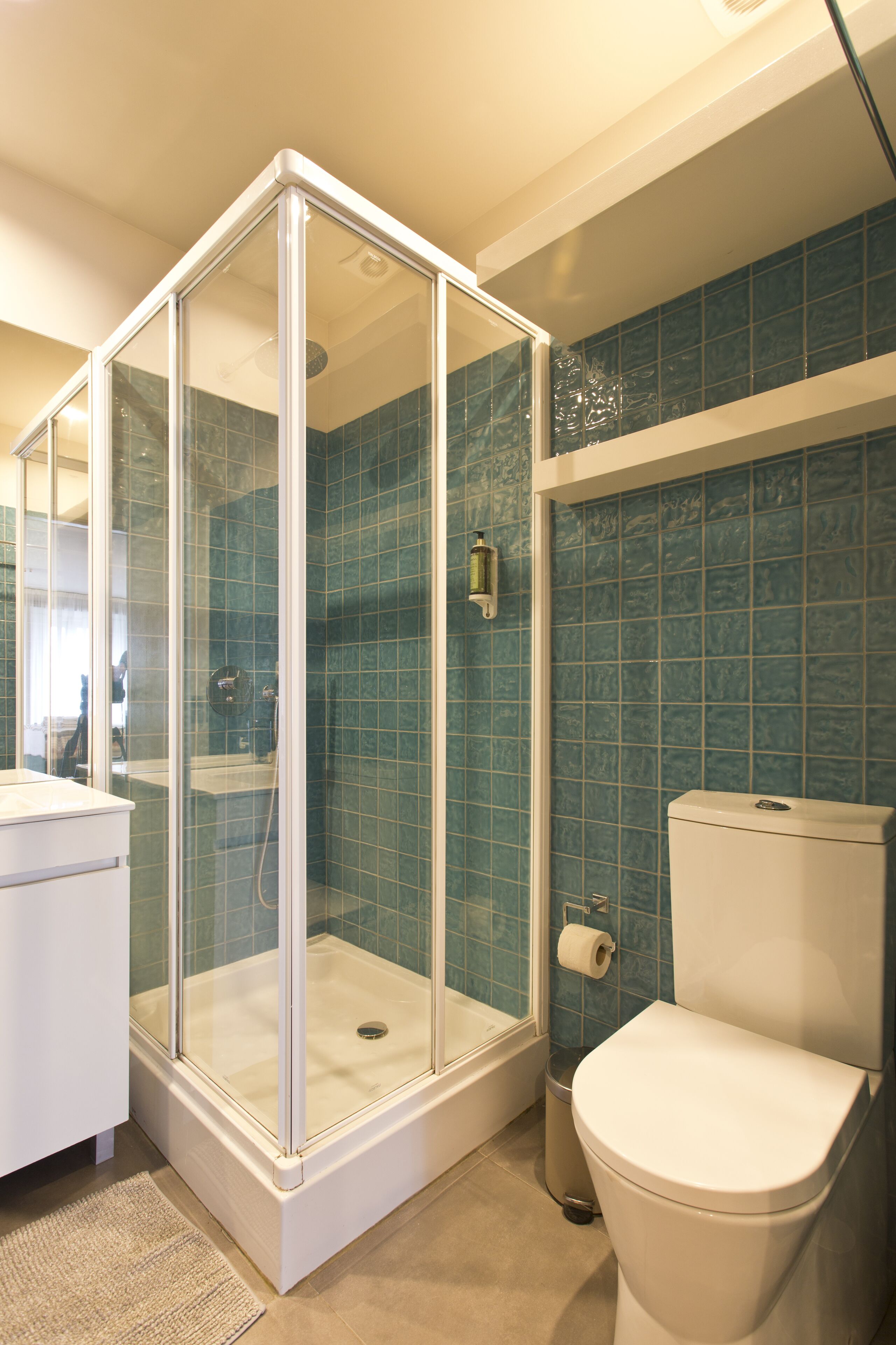 Un baño con ducha de vidrio, inodoro y lavamanos.