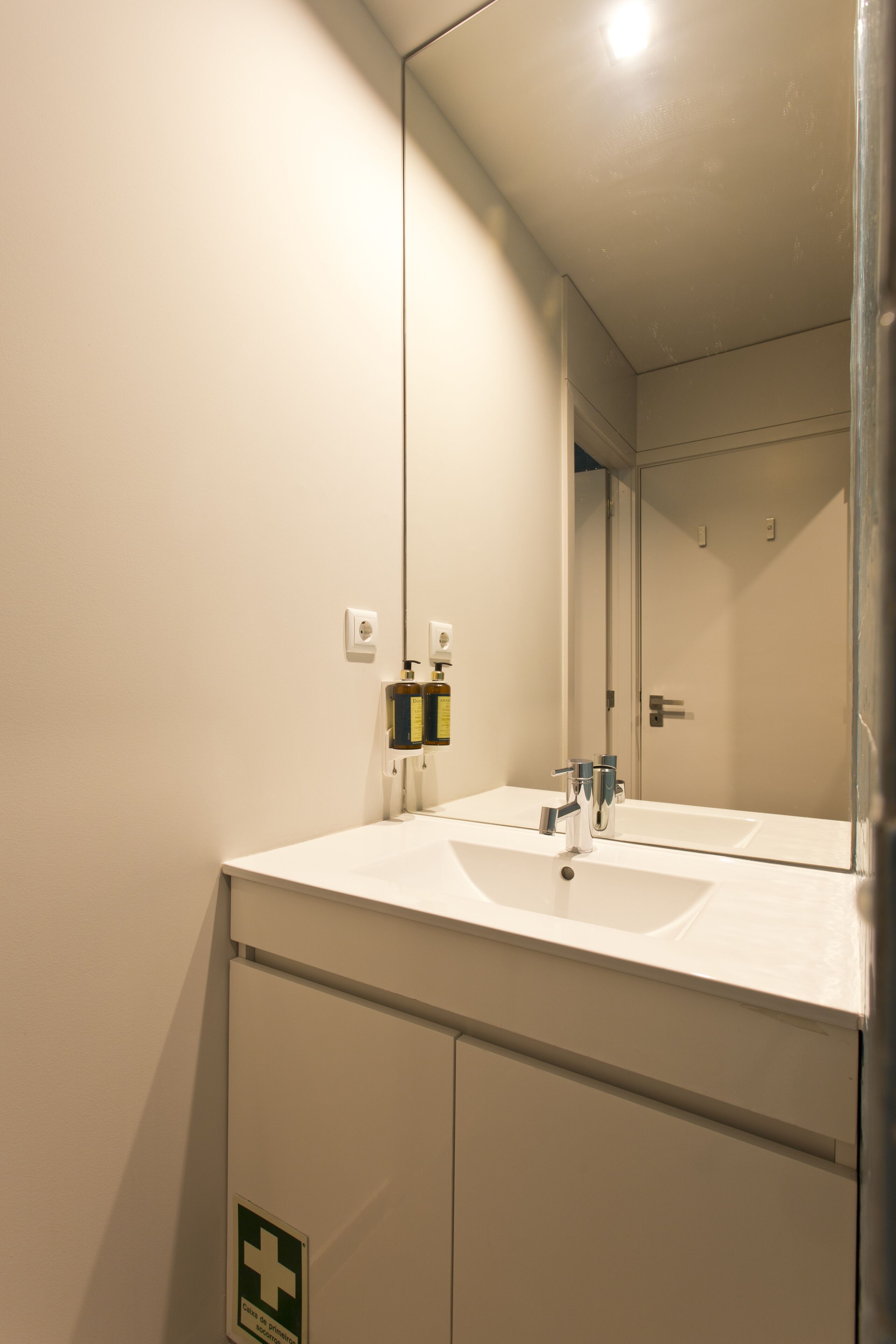 A bathroom with a white sink, a mirror, and a door.