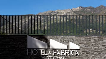 A sign for HOTEL & FABRICA Rustic luxury with a mountainous backdrop.