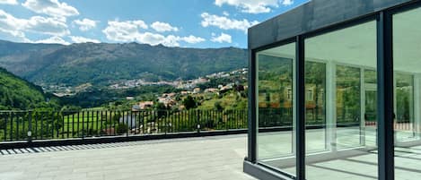 A modern building with large glass windows overlooking a mountainous landscape.