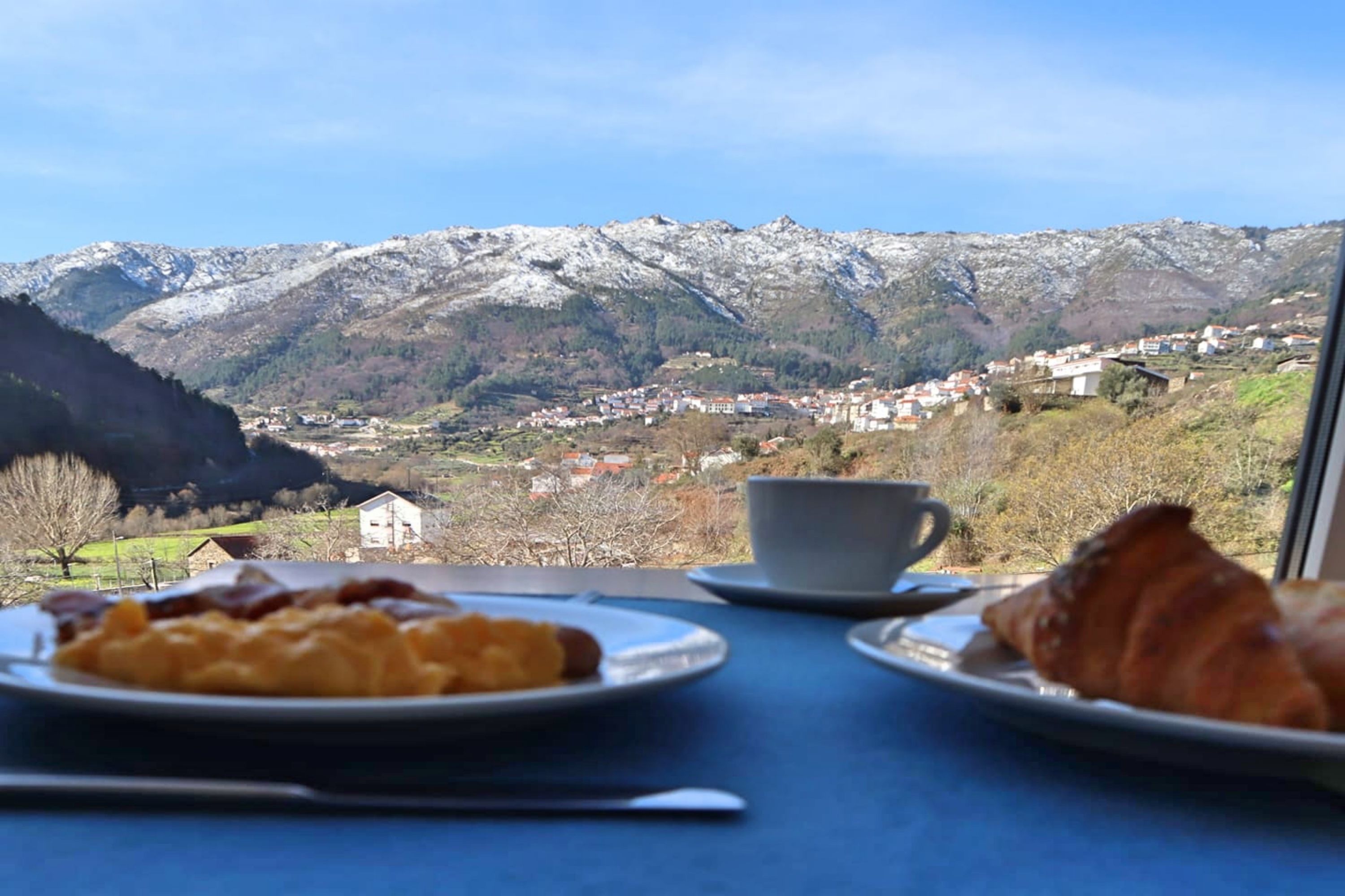 A table with breakfast items and a scenic mountain view.