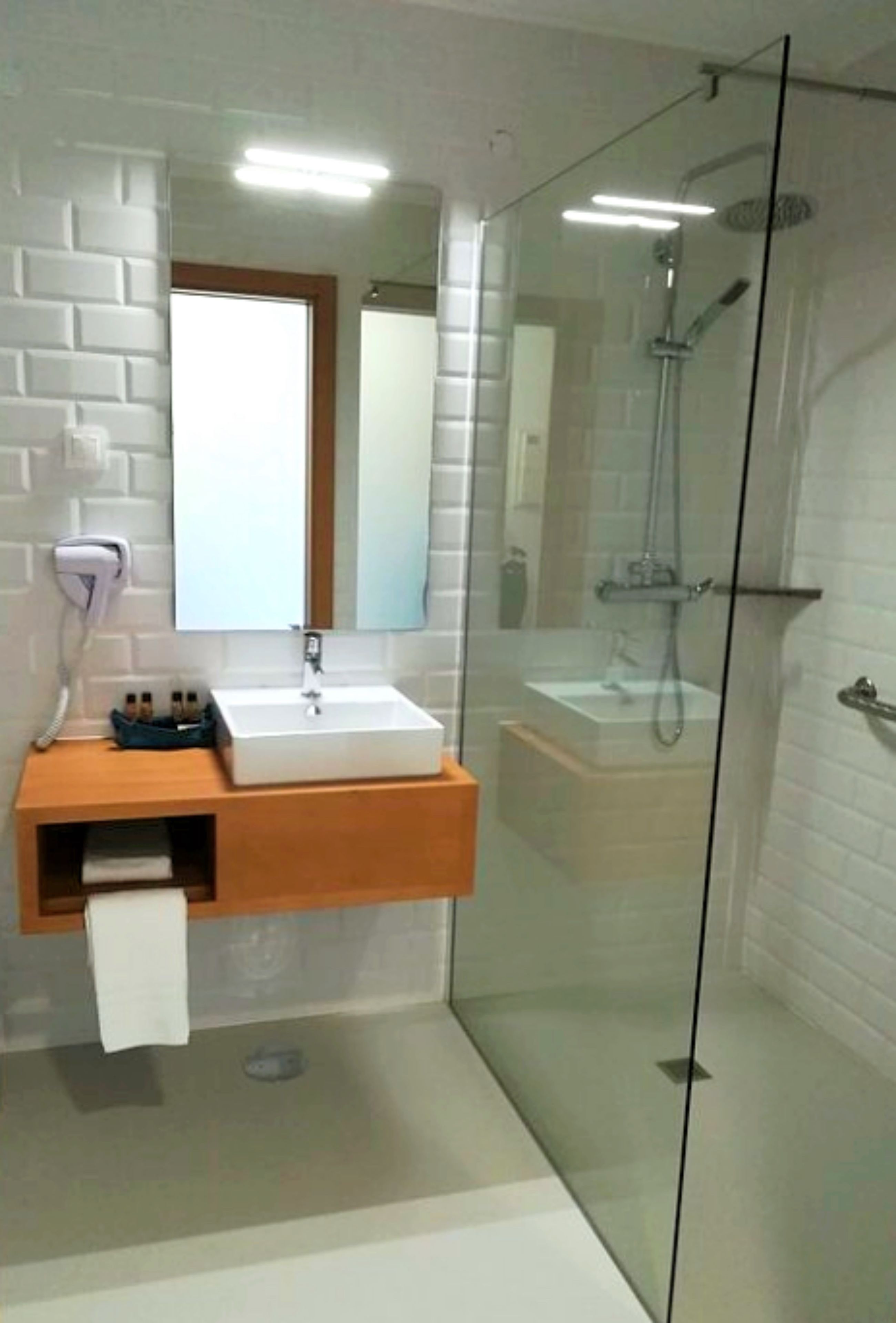 A modern bathroom with a glass-enclosed shower, a white sink, and a mirror above it.