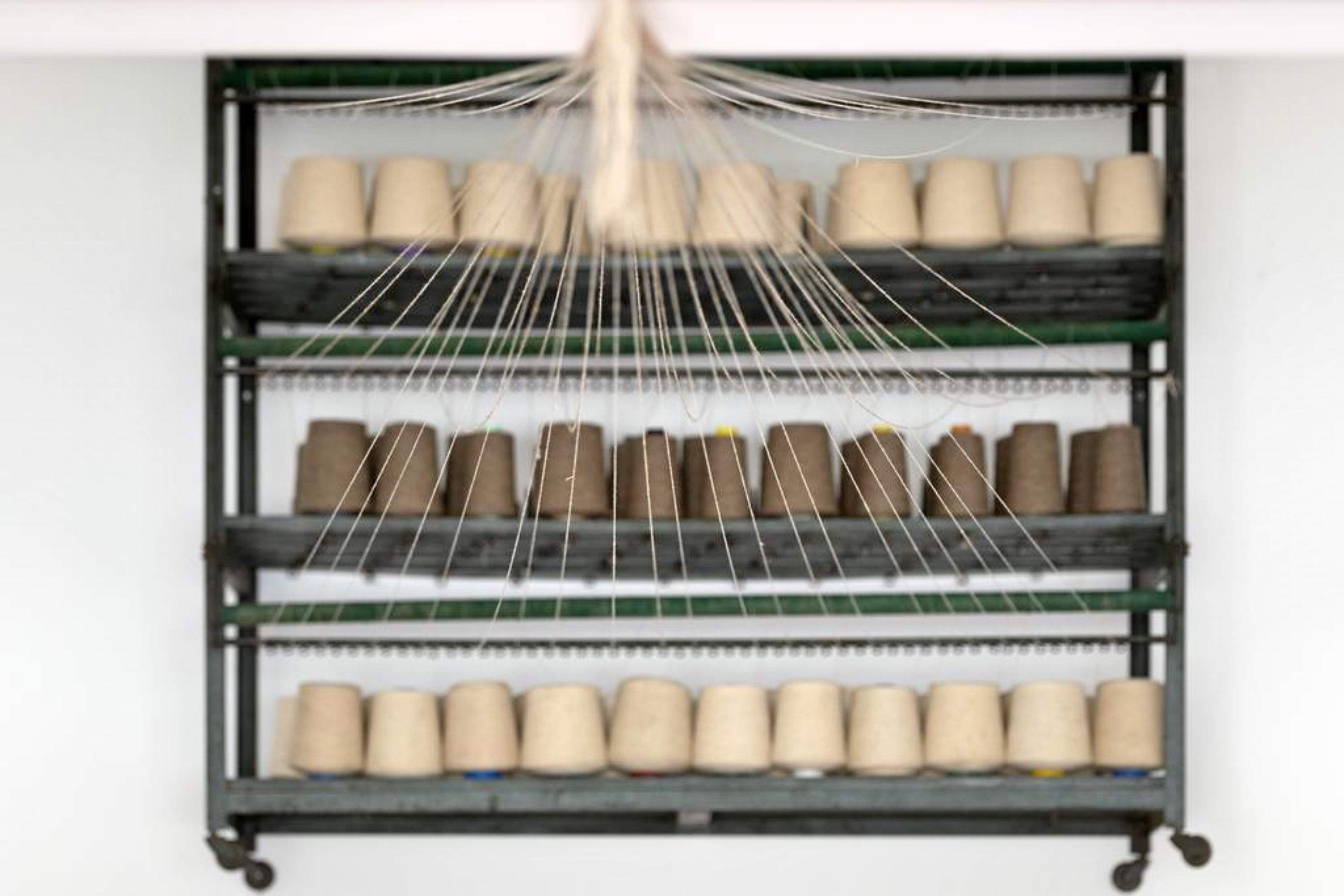 A rack with multiple shelves holding rolls of beige and brown paper towels.