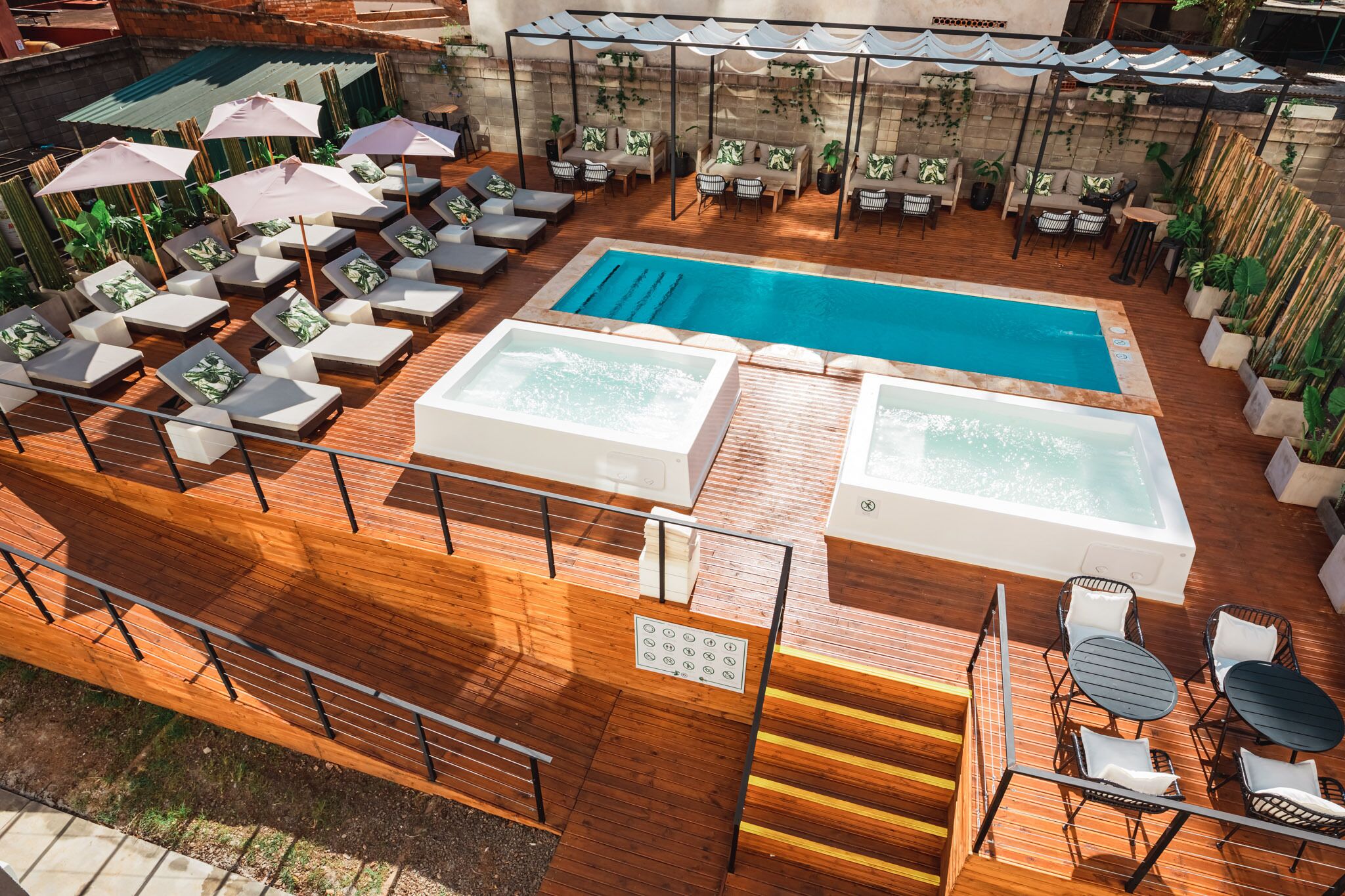 An outdoor swimming pool area with lounge chairs, a hot tub, and a wooden deck.