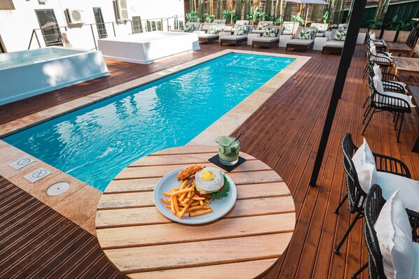 A poolside area with a wooden deck, a pool, and outdoor seating.