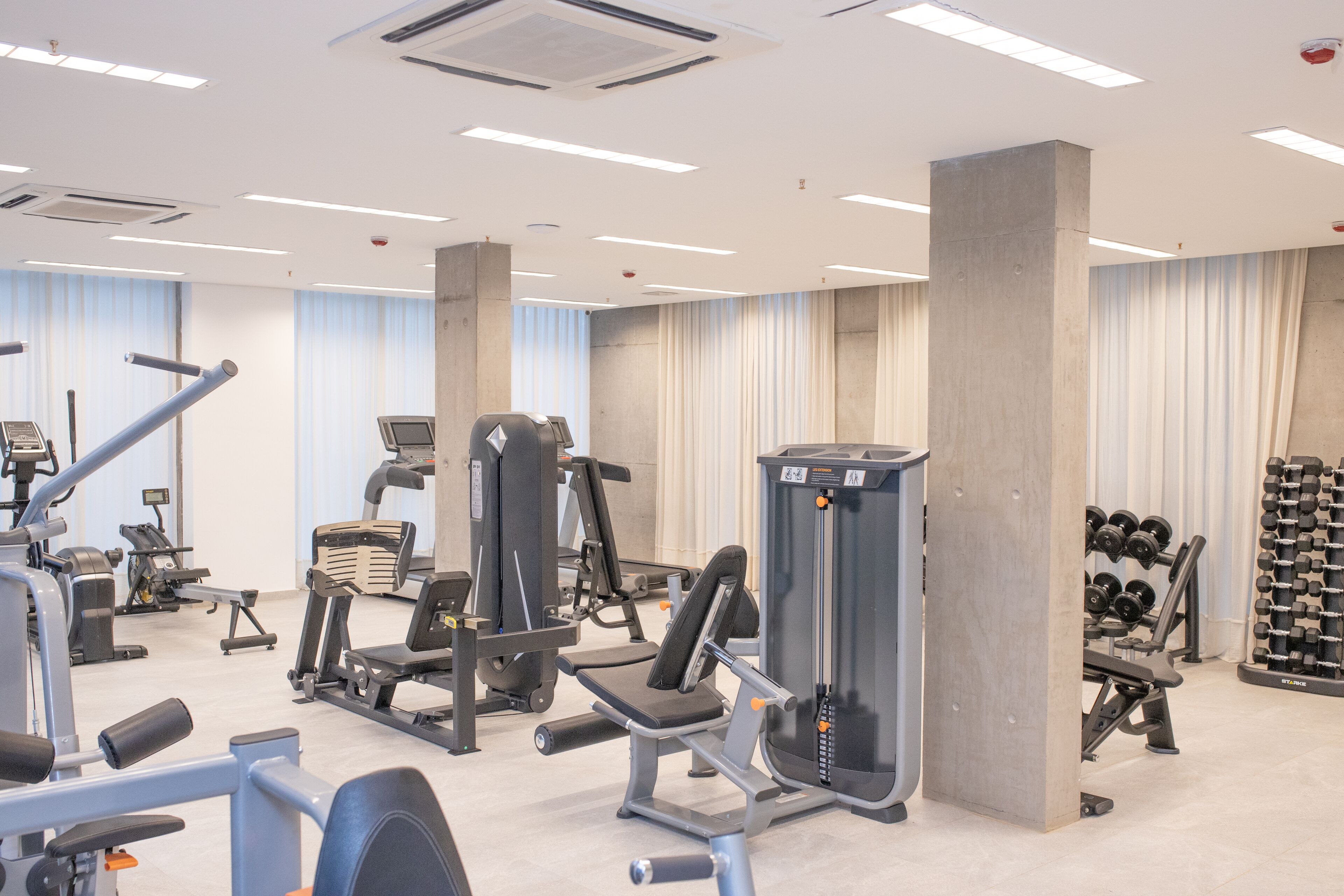 Un gimnasio con diversos equipos de ejercicio, incluyendo cintas de correr, máquinas de pesas y mancuernas.