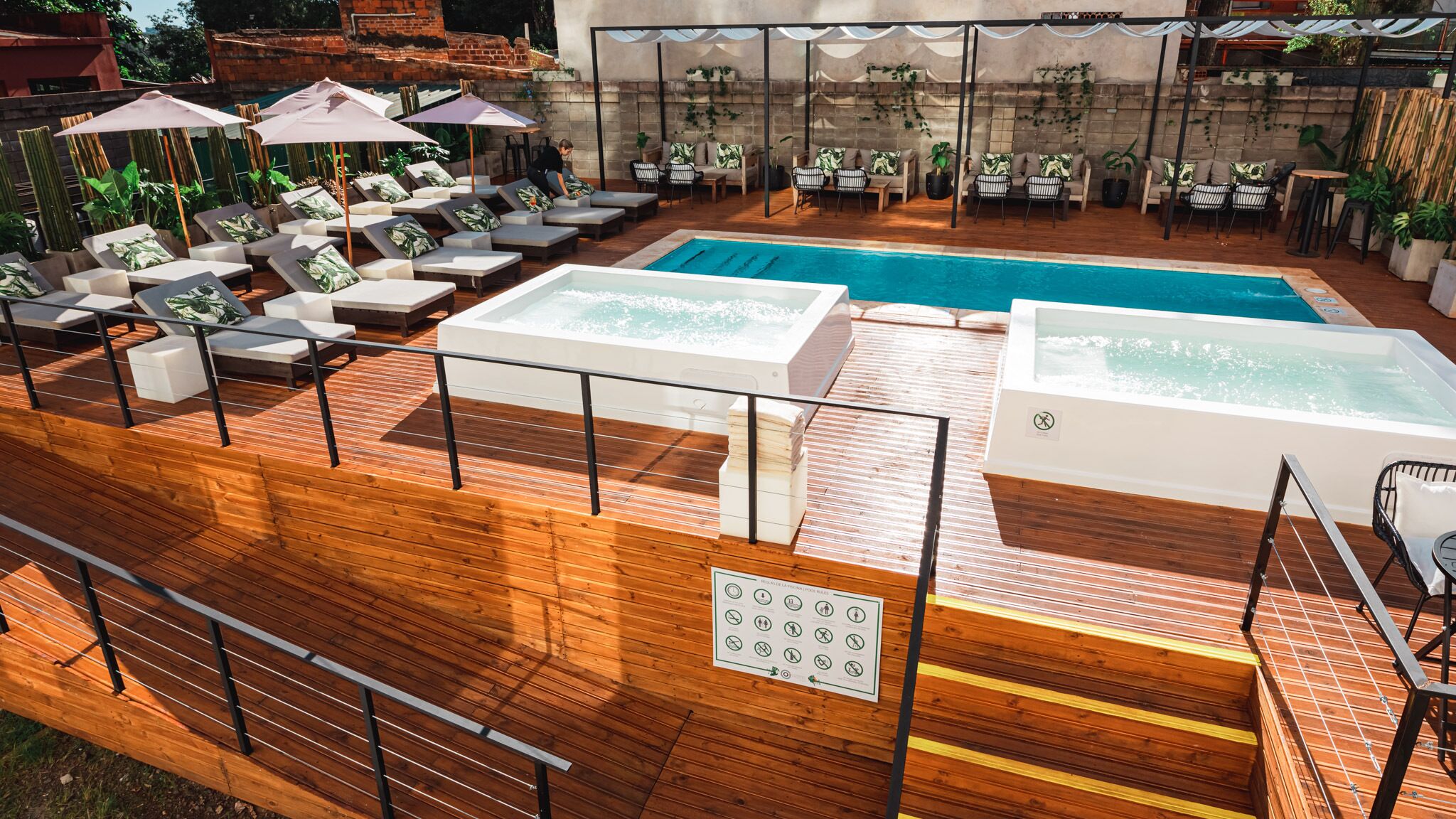 Ein Poolbereich auf dem Dach mit Liegestühlen, einem Whirlpool und einer überdachten Lounge.