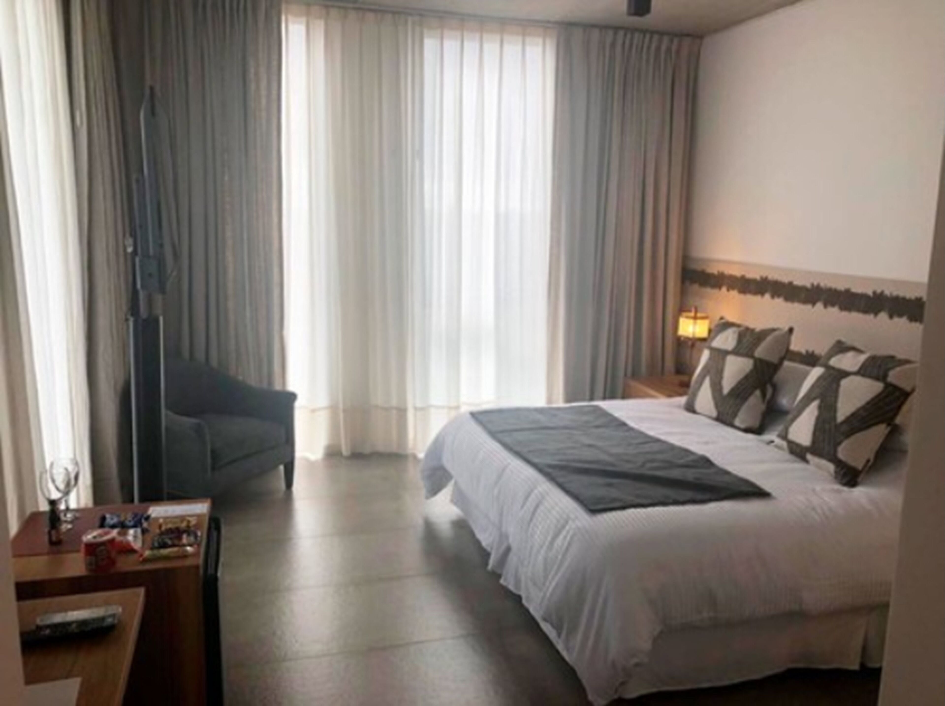 Una habitación de hotel con cama, escritorio, silla y lámpara.
