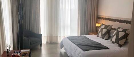 Una habitación de hotel con cama, escritorio, silla y lámpara.