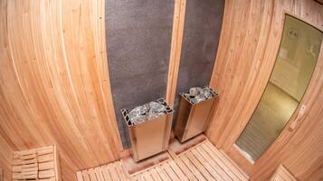 Una sauna con paredes y bancos de madera, una puerta de vidrio y suelo de baldosas.