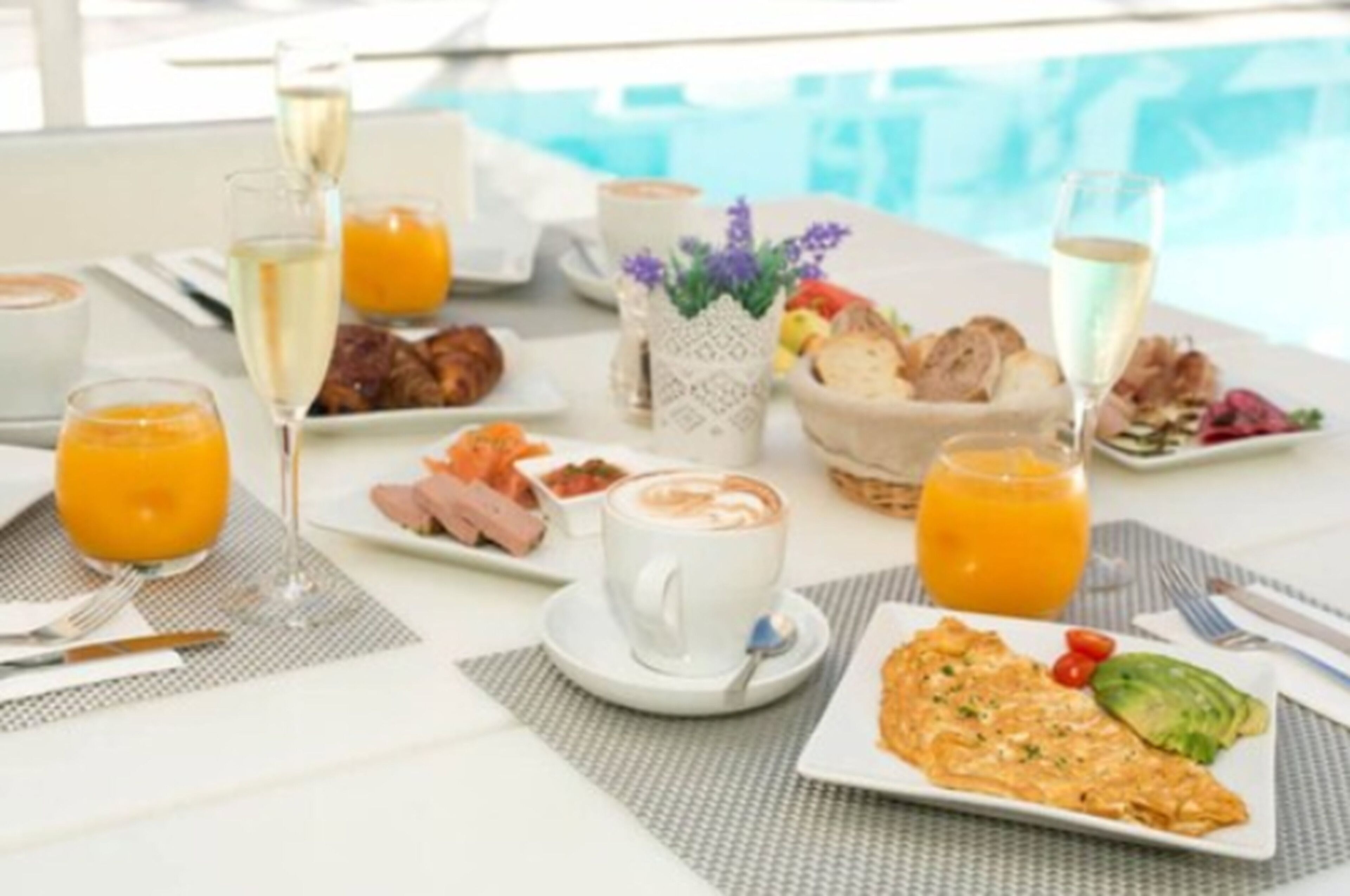 Desayuno con diversas opciones de comida y bebidas, y vista a una piscina.