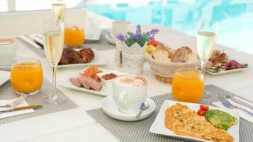 Desayuno con diversas opciones de comida y bebidas, y vista a una piscina.
