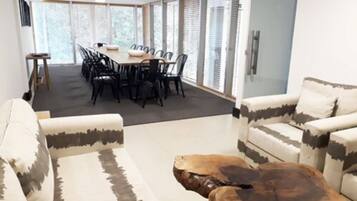 A modern living room with a dining area. There are two sofas, a coffee table, and a dining table with chairs.