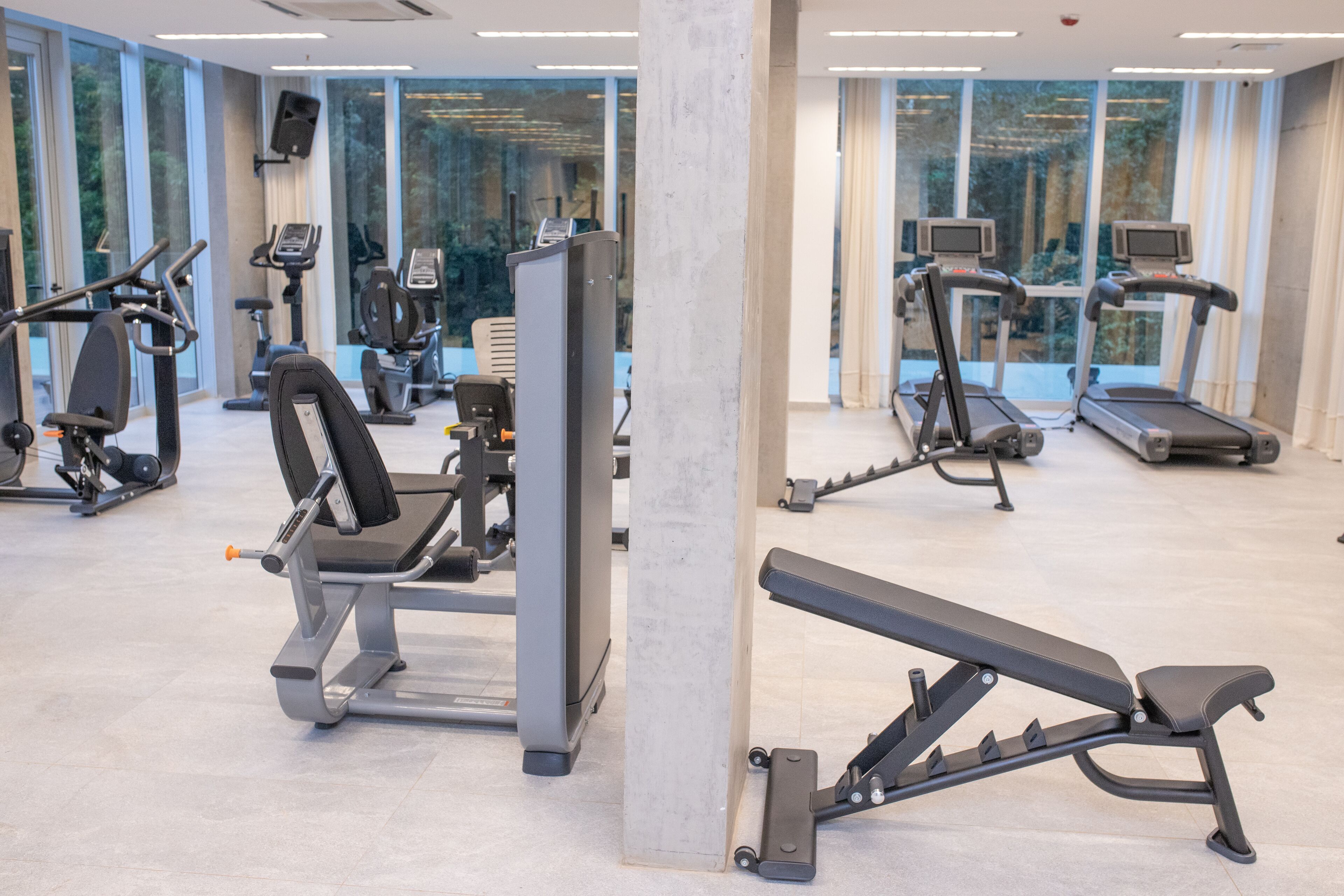 A gym with various exercise equipment, large windows, and a clean, modern design.