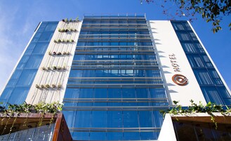 Un moderno edificio de hotel con fachada de vidrio, un logotipo destacado y una señal que indica que es un hotel.
