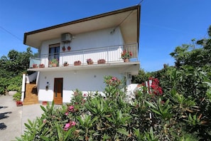 Ein zweistöckiges Gebäude mit Balkon, einer Tür und Topfpflanzen.