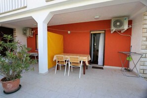 Un patio con una mesa, sillas, un equipo de aire acondicionado y una planta en maceta.