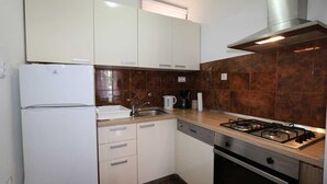 A kitchen with white cabinets, a stainless steel range hood, a gas stove, a dishwasher, and a refrigerator. - Apartment Grskovic G. Setaliste A4 (Silo - island Krk)