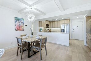 Een moderne keuken met een centraal eiland, houten stoelen en een eettafel gedekt voor vier personen.
