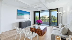 A modern living room with a large window, a flat-screen TV, a coffee table, and a sofa. - Anchorage Resort 3rd Floor Two Bedroom Condo with Beach Access (Siesta Key)