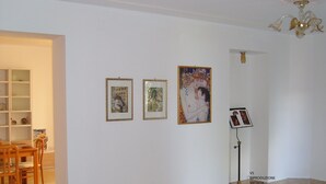 A room with a dining area, a white wall with framed artwork, and a floor lamp. - Villa Sandra (Giulianova)