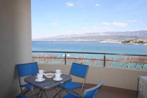 Een balkon met een tafel en stoelen, met uitzicht op de kust.
