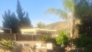 A spacious outdoor patio area with tiled flooring, wicker furniture, and potted plants. - 3 bed apartment, 1 bathroom, Large Private Patio & Garden, Mountain views, (Pizzo)