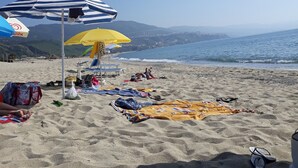Una playa con sombrillas, toallas y sillas de playa.