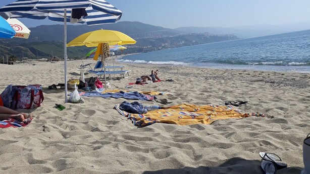 A beach with umbrellas, towels, and beach chairs. - 3 bed apartment, 1 bathroom, Large Private Patio & Garden, Mountain views, (Pizzo)