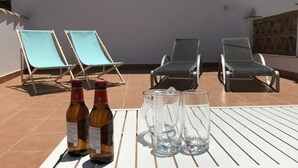 Terrassa amb dues ampolles de vi, dues copes i quatre cadiretes de relax.