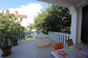 Un patio con una mesa redonda, sillas y plantas en macetas.