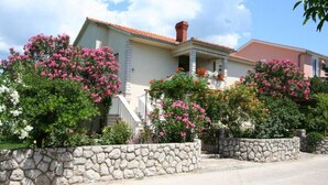 A house with a stone wall, pink flowering bushes, and a clear sky. - Apartment Grskovic G. Setaliste A2 (Silo - island Krk)