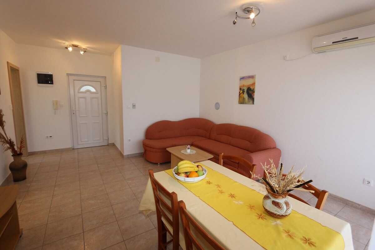 En spiseplads med et bord dækket til to personer, en sofa og en vægmonteret aircondition.