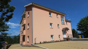 A multi-story building with a flat roof, a balcony on the second floor, and a small entrance with steps. - Apartment Dudovic Damir A2 nr 2 (Silo - island Krk)