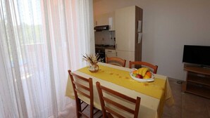 A dining area with a table set for two, a fruit bowl, and a television on a stand. - Apartment Dudovic Damir A2 nr 2 (Silo - island Krk)