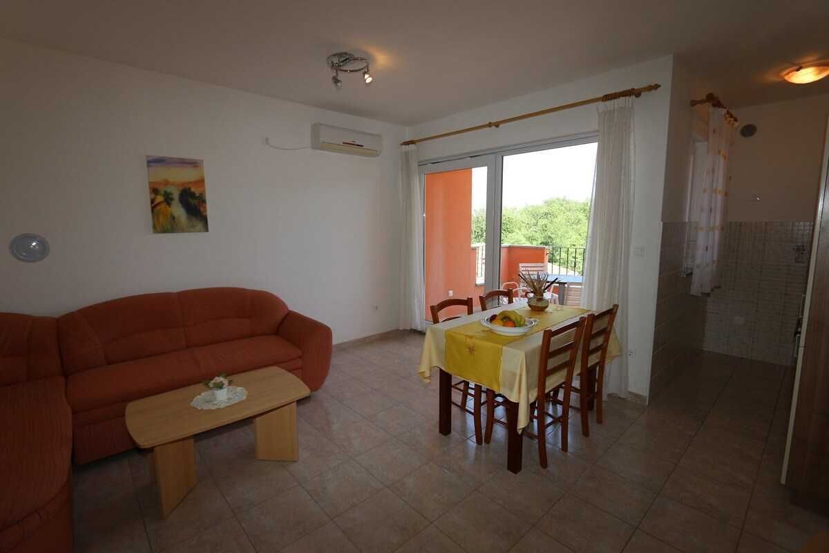 Ein Wohnzimmer mit einer Couch, einem Esstisch mit Stühlen, einer Bank und einem Bild an der Wand.