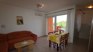 A living room with a sofa, a dining table with chairs, a bench, and a painting on the wall. - Apartment Dudovic Damir A2 nr 2 (Silo - island Krk)