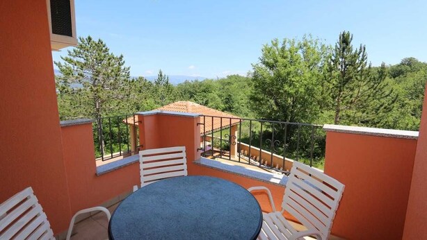 A balcony with a round table and white chairs, overlooking a forested area. - Apartment Dudovic Damir A2 nr 2 (Silo - island Krk)