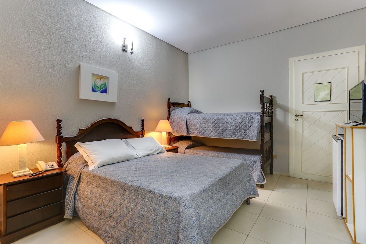 A bedroom with two beds, a nightstand with a phone, a lamp, and a door with a mirror.