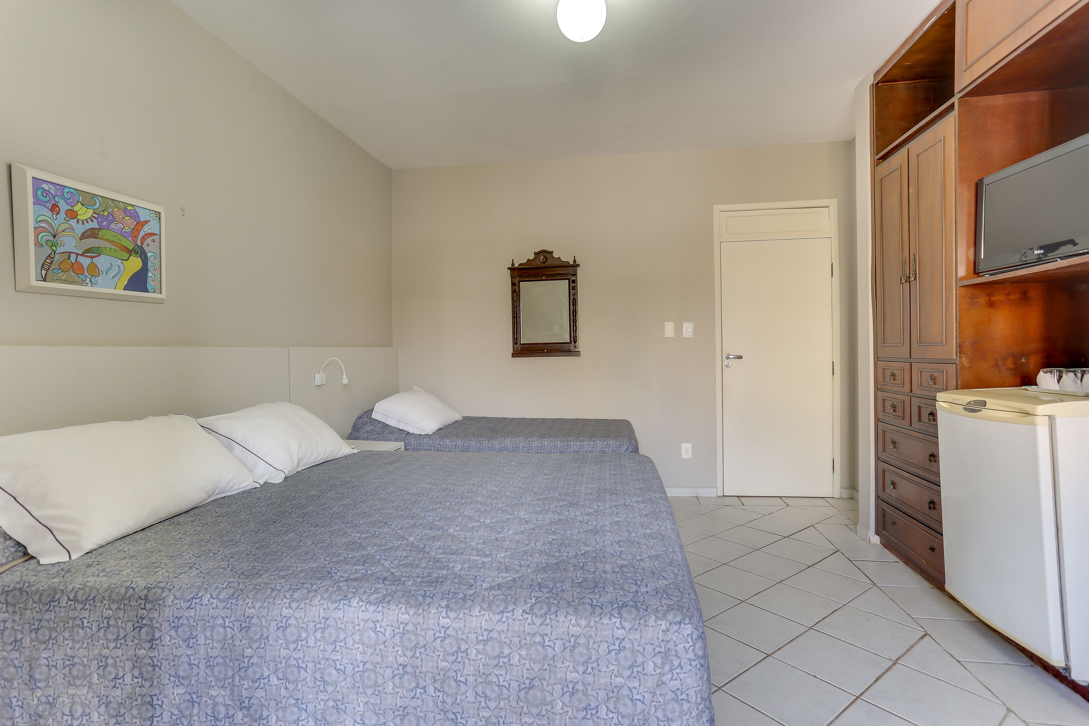 Une chambre avec deux lits, une télévision, un miroir et une armoire.