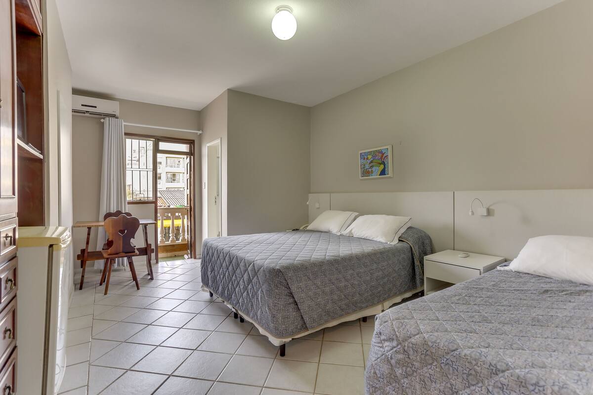 A bedroom with a bed, a chair, a nightstand, and a window.