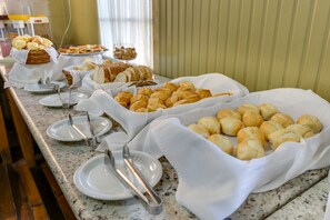 En buffé med ett urval av olika bakverk, inklusive bröd och småkakor, som är upplagt på en marmorskiva.