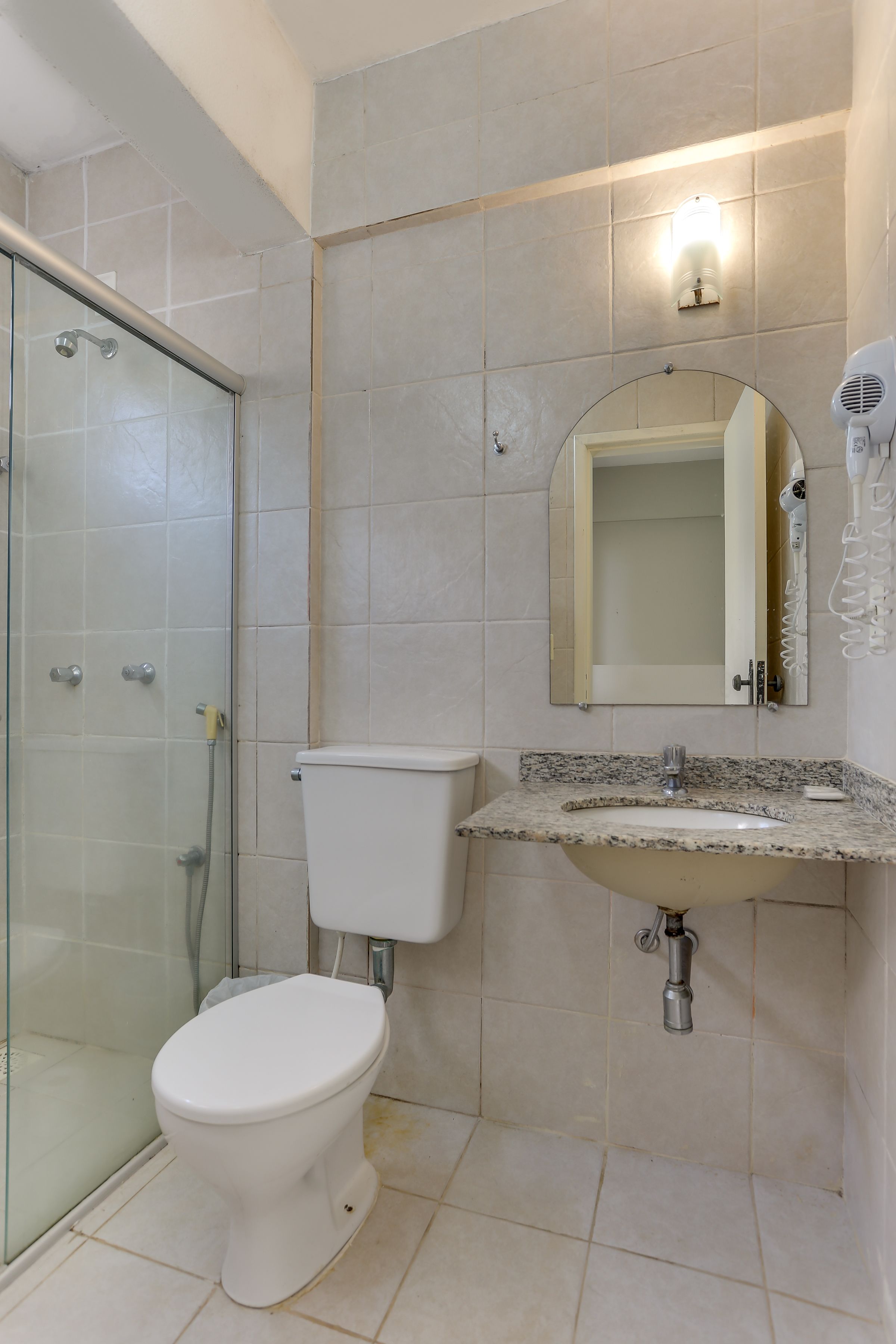 A bathroom with a toilet, sink, and glass shower enclosure.