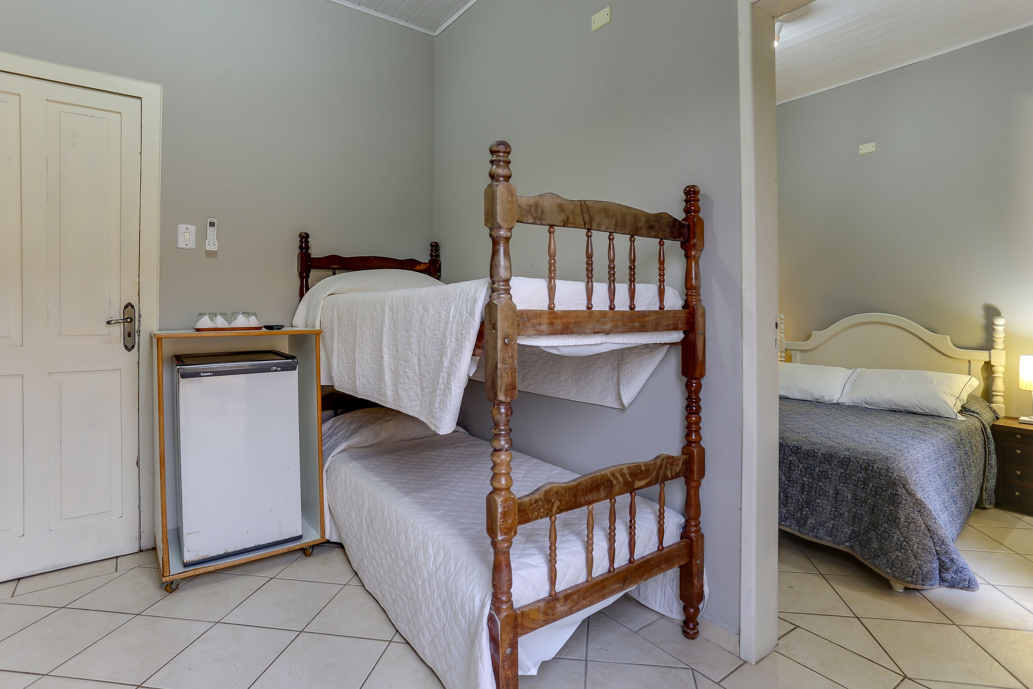 Una stanza con un letto a castello, un piccolo frigorifero e un comodino.