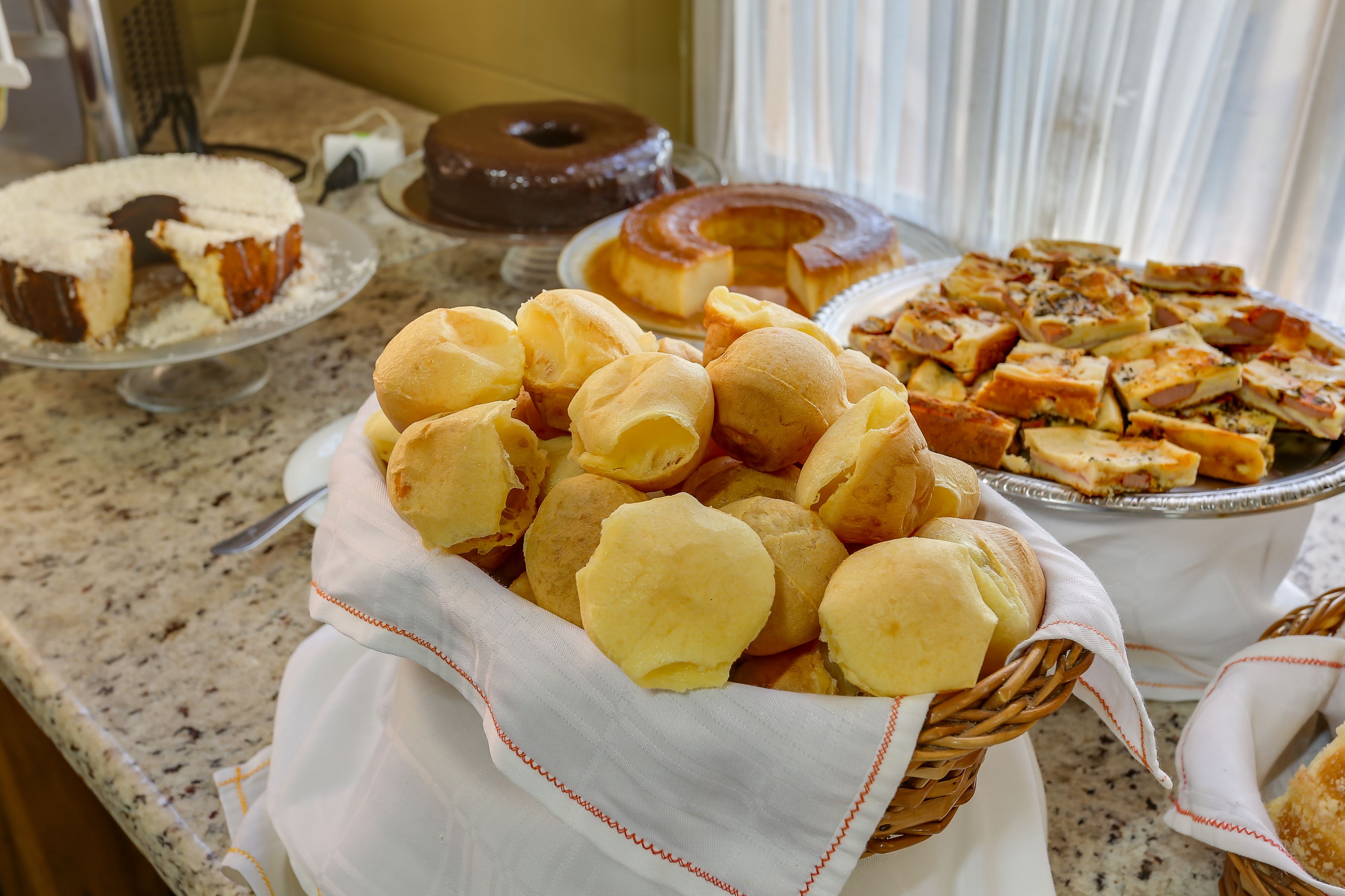 A buffet table with various baked goods including bread rolls, a cake, and pastries.